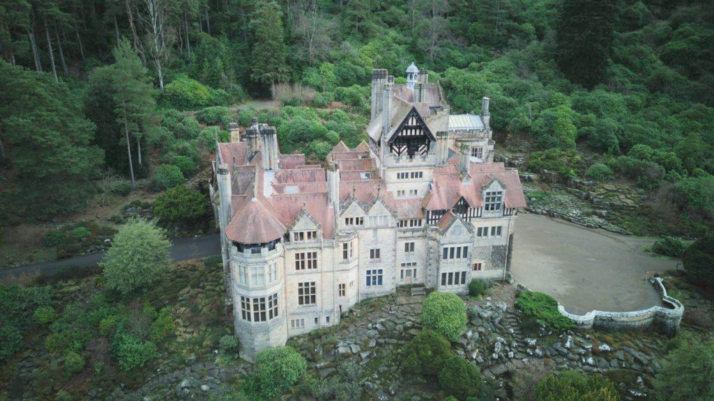 View of a picturesque cragside housenestled in the midst of a lush forest