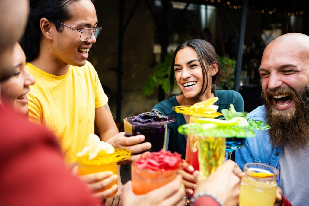 Happy multiethnic group of friends drinking trendy cocktails in a terrace bar